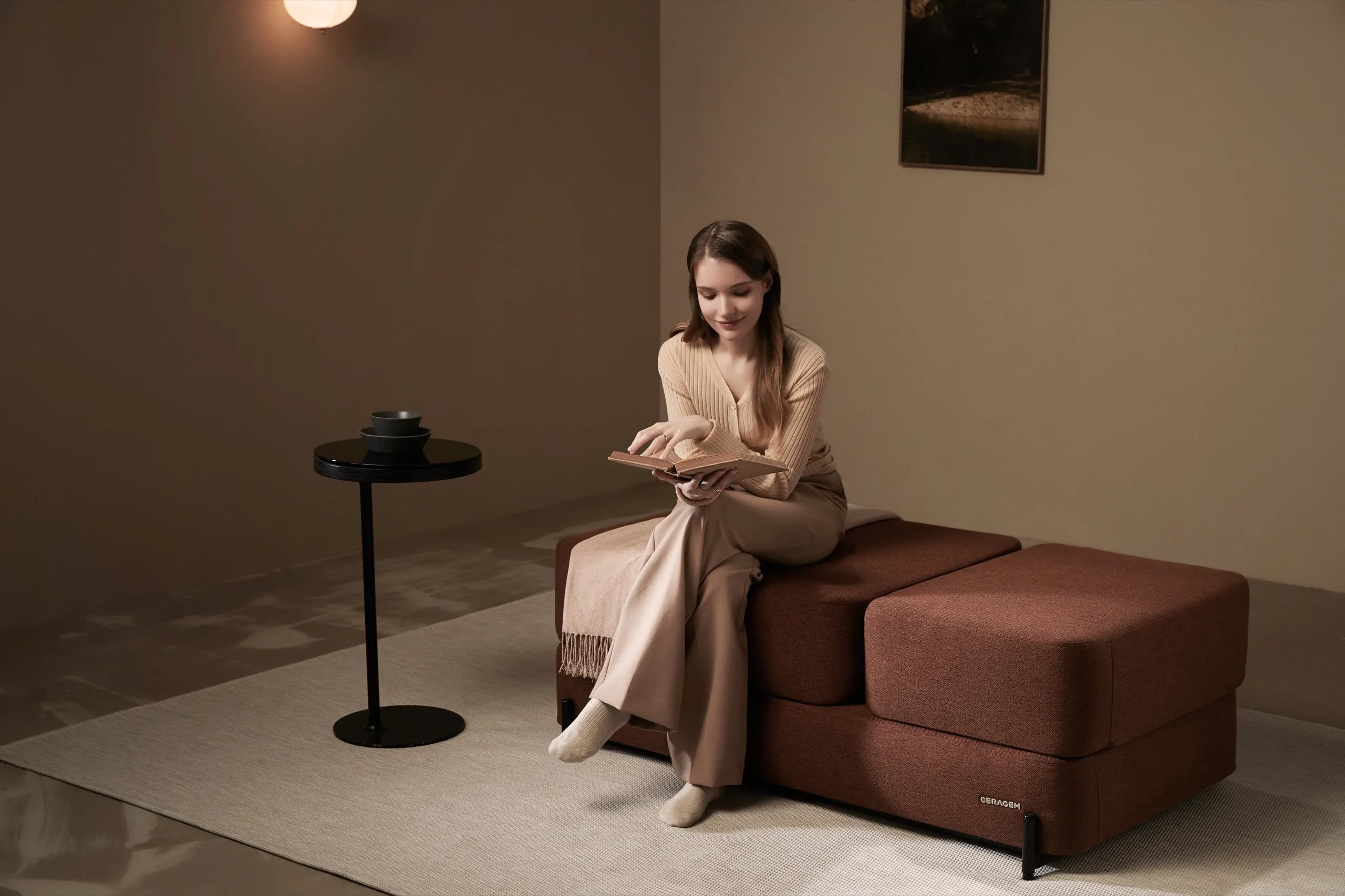 A woman reading a book while seated on the Master S4 in a warm-toned living room